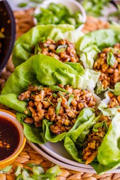 lettuce wraps filled with meat and seasoning on a plate next to dipping sauce