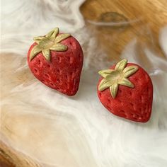 two red strawberries sitting on top of a wooden table