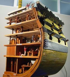 a wooden model of a boat with people on the deck and in it's hull