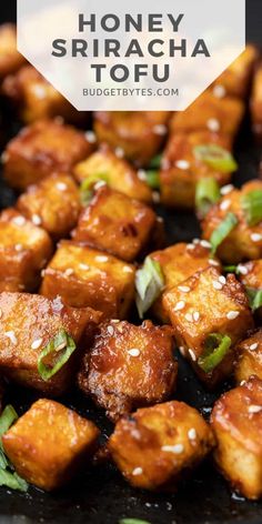 honey sriraca tofu on a black plate with green onions and sesame seeds