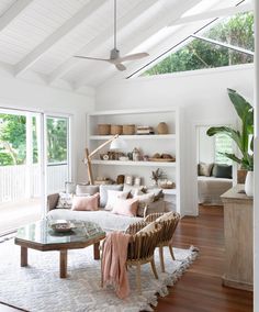 a living room filled with furniture next to a window covered in plants and bookshelves