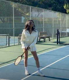 a woman standing on a tennis court holding a racquet in one hand and looking up at the sky