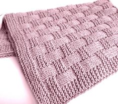 a pink knitted blanket laying on top of a white table