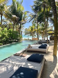 lounge chairs are lined up next to the swimming pool at an exotic beachfront resort