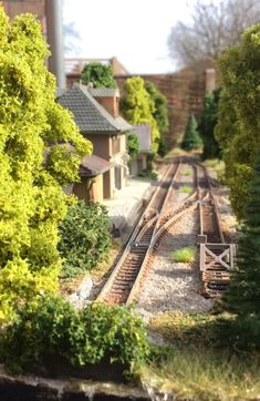 a model train track surrounded by trees and buildings