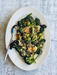 a white plate topped with broccoli covered in parmesan cheese and crumbs