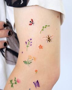 a woman's stomach with colorful flowers and butterflies on her side, while she is wearing a white shirt