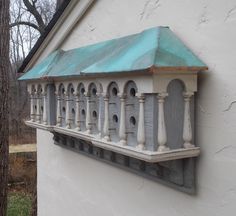 a bird house is mounted on the side of a building with blue roof and white pillars