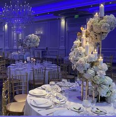 the tables are set with white flowers, candles and place settings for an elegant dinner