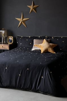 two gold stars hang on the wall above a bed in a bedroom with black walls