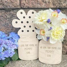 two mason jars with flowers in them sitting on the ground