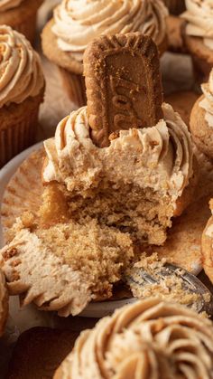 cupcakes with frosting and a bite taken out of the top one on a plate