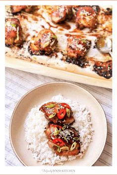 a white plate topped with rice and meat covered in sauce next to a baking sheet