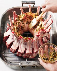 a person holding a knife over some raw meat on a grill with spices and seasonings