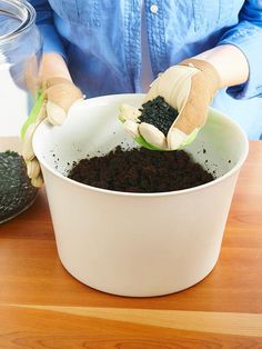 a person wearing gloves scooping dirt into a container