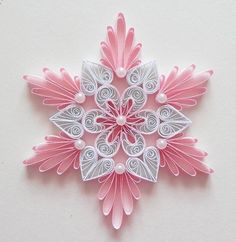 a pink and white paper snowflake with swirls on it's sides