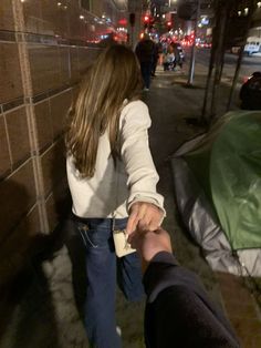 two people are holding hands on the sidewalk