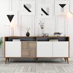 a white and wood sideboard with three black geometric shapes on the wall above it