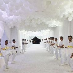 a group of men standing in a room with white balloons on the ceiling and one man holding a plate