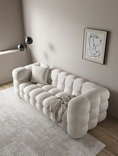 a large white couch sitting on top of a wooden floor next to a lamp and rug