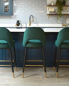 two green chairs sitting in front of a kitchen counter with blue cabinets and white counters