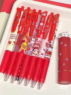 six red pens are lined up in a row on a tray next to a pen holder