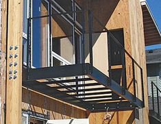 a metal balcony attached to the side of a wooden building with windows and balconies