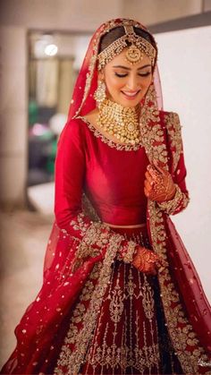 a woman in a red and gold bridal gown with her hands on her chest