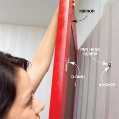 a woman is measuring the length of a wall with red tape and an arrow on it