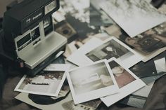 an old polaroid camera sitting on top of a table filled with pictures and photos