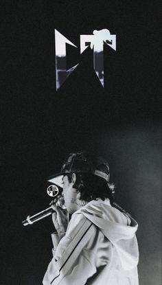 a man holding a microphone in his right hand and wearing a baseball cap on top of his head