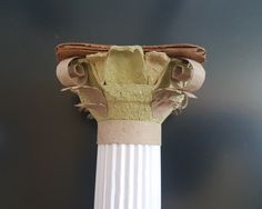 a close up of a white column with some green stuff on it's top