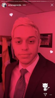 a man in a suit and tie is looking at the camera with pink light on his face