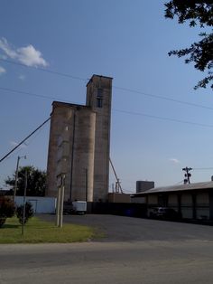 an old grain silo sits in the middle of a parking lot next to a building