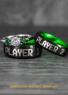 two wedding rings with the words player 1 and 2 written on them, sitting next to each other