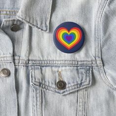 a button with a rainbow heart in the center on a denim jacket pocketed up