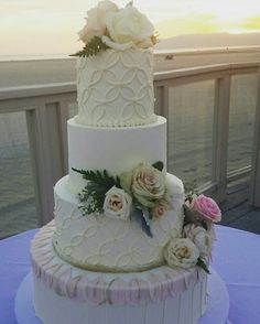 a three tiered wedding cake with white frosting and pink flowers on the top