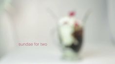 an ice cream sundae in a glass on a white surface with the words sunday for two above it