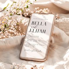 an iphone case sitting on top of a white sheet next to some flowers and branches