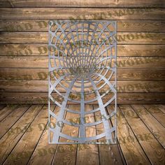 a metal sculpture sitting on top of a wooden floor next to a wood plank wall