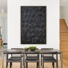 a dining room table with four chairs and a bowl of fruit on it