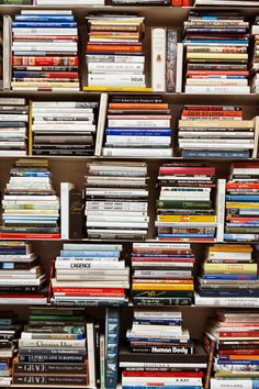 a book shelf filled with lots of books on top of each other and stacked high