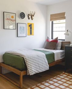 a bed sitting in a bedroom next to a window with pictures on the wall above it