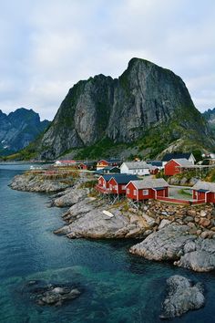 small red houses on the shore of a body of water with mountains in the background