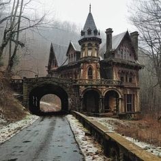 an old abandoned building with a bridge leading to it and snow on the ground in front