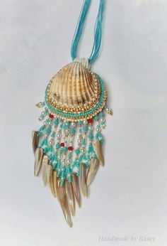 a necklace with shells and beads hanging from a blue cord on a white surface,