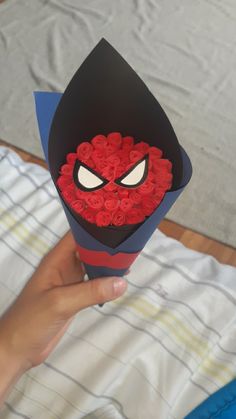 someone is holding up a box with roses in the shape of a spider man