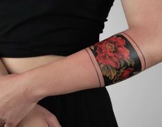 a woman's arm with a flower tattoo on it and a black dress underneath