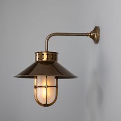 an old fashioned wall lamp with a white light on it's side, against a gray background