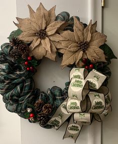 a christmas wreath with poinsettis and ribbons hanging on the front door handle